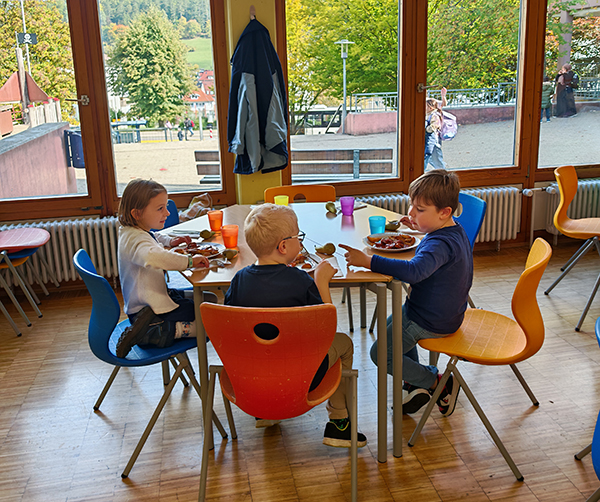 3 Schulkinder in der Mensa beim Mittagstisch